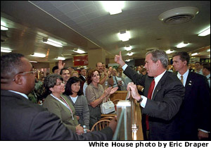 President George Bush gives a thumbs up to a crowded cafeteria while visiting the Pentagon September 17. After meetings, the President talked with hundreds of employees throughout the complex. White House photo by Eric Draper.