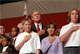 Accompanied by several children, President George W. Bush says the pledge of allegiance at the California's Business Association Oct. 17. White House photo by Eric Draper.