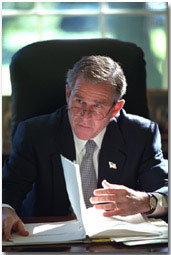 Working at his desk in the Oval Office, President George W. Bush prepares for his first meeting with the Homeland Security Team Oct. 29, 2001. White House photo by Eric Draper.