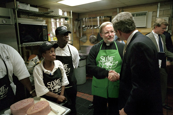 Visiting the kitchen of So Others Might Eat charity, President George. W. Bush greets director Father Adams and other volunteers at the Washington D. C. site Nov. 20. Started in 1970, the program serves breakfast and lunch daily to homeless. White House photo by Tina Hager.