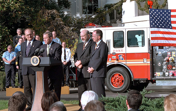 Accompanied by firemen and other distinguished guests, President George W. Bush speaks during a ceremony held to honor the gift of a new firetruck for city of New York on the South Lawn Dec. 19. Donated by the state of Louisiana, the "Spirit of Louisiana," will replace one of the 35 firetrucks that were destroyed in the Sept. 11 attacks. Standing with the President is Ronald Goldman, (left) Louisiana Governor Mike Foster, (center) and Louisiana Representative Hunt Downer. White House photo by Tina Hager.