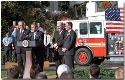 Accompanied by firemen and other distinguished guests, President George W. Bush speaks during a ceremony held to honor the gift of a new firetruck for the city of New York on the South Lawn Dec. 19. Donated by the state of Louisiana, the 