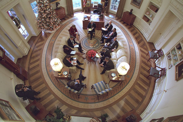 President George W. Bush hosts a meeting in the Oval Office decorated with the new presidential rug on December 20, 2001. The rug, which is unique to the Bush administration, arrived earlier in the week and was unveiled to the media on Friday December 21, 2001. Members from the Office of Homeland Security and other White House staff attended the meeting. The participants included (clockwise from the bottom), President George W. Bush, Governor Tom Ridge, Dr. Condoleezza Rice, Admiral Steve Abbot, Karen Hughes, Dean McGrath, Karl Rove, Albert Hawkins, Mitch Daniels, Josh Bolton, and Andy Card. White House Photographer Paul Morse is at left. White House photo by Paul Morse.