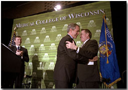 President George W. Bush embraces Secretary of Health and Human Services and former Wisconsin Governor Tommy Thompson after speaking about healthcare reform issues at the Medical College of Wisconsin in Milwaukee, Wis., February 11, 2002. Wisconsin's current governor Scott McCallum is also pictured. White House photo by Paul Morse.