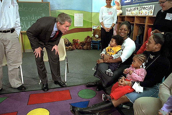 President George W. Bush talks with a little singer during his visit to the People's Emergency Center, a homeless shelter for woman and children, in Philadelphia, March 11. The President visited the shelter to thank volunteers for their work and sing songs such as "Itsy-bitsy spider" with children. White House photo by Eric Draper.