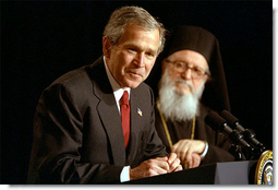 Accompanied by His Eminence Archbishop Demetrios, Primate of Greek Orthodox Church of America, President George W. Bush addresses attendees of the Greek Independence Day Ceremony in the Eisenhower Executive Office Building March 25, 2002. "America and Greece are strong allies, and we're strategic partners," said President Bush. "Our nation has been inspired by Greek ideals, and enriched by Greek immigrants." White House photo by Paul Morse.
