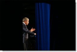 Photographed through stage curtains, President George W. Bush delivers his remarks on compassionate Conservatism at Parkside Hall in San Jose, Ca., Tuesday, April 30. Eric Draper.