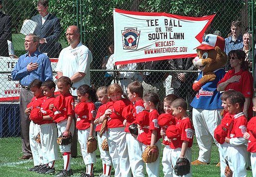 President George W. Bush and White House Tee Ball Commissioner Cal Ripken, Jr., stand with the players during the singing of the national anthem on the opening day of the 2002 White House Tee Ball season on the South Lawn Sunday, May 5. White House photo by Tina Hager.