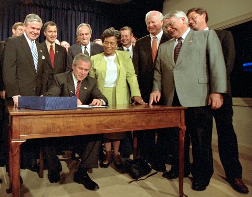 Accompanied by Congress members, President George W. Bush signs the Farm Security and Rural Investment Act of 2002 in the Dwight D. Eisenhowser Executive Office Building May 13. "This bill is generous, and will provide a safety net for farmers. And it will do so without encouraging overproduction and depressing prices. It will allow farmers and ranchers to plan and operate based on market realities, not government dictates," said the President. White House photo by Eric Draper.