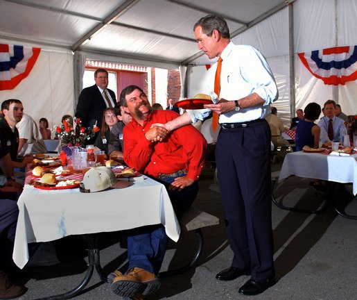 President George W. Bush greets Texas hog farmer George Fink before sitting down to eat during a barbeque picnic with pork producers and their families at the World Pork Expo in Des Moines, Iowa, Friday, June 7, 2002. White House photo by Eric Draper.