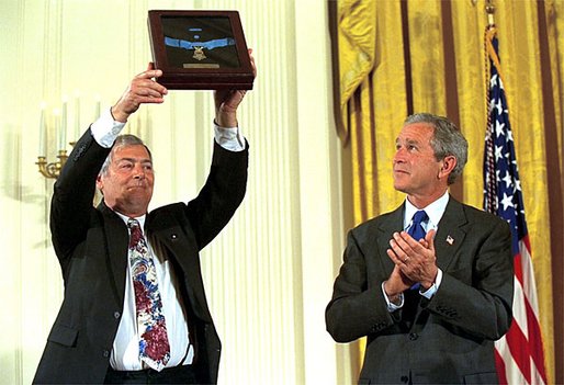 Steve Versace holds up the Medal of Honor that President George W. Bush presented to him on the behalf of his brother, Army Captain Humbert "Rocky" Versace, during a ceremony in the East Room, Monday, July 8. Executed in a POW camp in Vietnam, Captain Versace is the first serviceman awarded the medal for bravery as a prisoner of war. White House photo by Eric Draper.