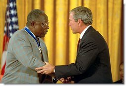 President George W. Bush presents the Presidential Medal of Freedom to baseball legend Henry Aaron during a ceremony at the White House, July 9, 2002. "The Presidential Medal of Freedom is the highest civil honor our nation can bestow. And we award it today to 12 outstanding individuals," said the President. "The men and women we honor span the spectrum of achievement. Some are fighters; others are healers; all have left an enduring legacy of hope and courage and achievement." White House photo by Eric Draper.