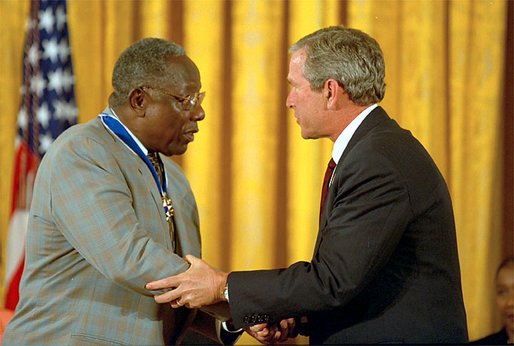 President George W. Bush presents the Presidential Medal of Freedom to baseball legend Henry Aaron during a ceremony at the White House, July 9, 2002. "The Presidential Medal of Freedom is the highest civil honor our nation can bestow. And we award it today to 12 outstanding individuals," said the President. "The men and women we honor span the spectrum of achievement. Some are fighters; others are healers; all have left an enduring legacy of hope and courage and achievement." White House photo by Eric Draper.