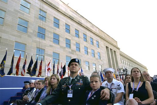 Sitting in front of the rebuilt section of the Pentagon, service personnel and families listen to President George W. Bush at the Pentagon Observance Wednesday, Sept. 11. "One year ago, men and women and children were killed here because they were Americans. And because this place is a symbol to the world of our country's might and resolve," said the President. "Today, we remember each life. We rededicate this proud symbol and we renew our commitment to win the war that began here." White House photo by Eric Draper.
