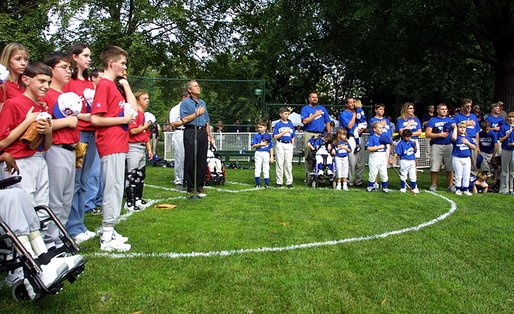 President George W. Bush listens to the National Anthem with T-Ball teams East Brunswick New Jersey Babe Ruth Buddy Ball League Sluggers in red and the Waynesboro Little League Challenger Division Sand Gnats in blue from Waynesboro, Virginia Sunday September 22, 2002 on the South Lawn of the White House. White House photo by Paul Morse.