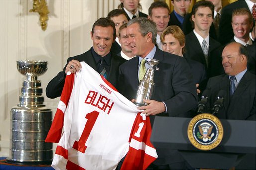Receiving a jersey from team captain Steve Yzerman, President George W. Bush welcomes the Detroit Red Wings, winners of the NHL 2002 Stanley Cup Championship, to the East Room of the White House Friday, Nov. 8. White House photo by Paul Morse.