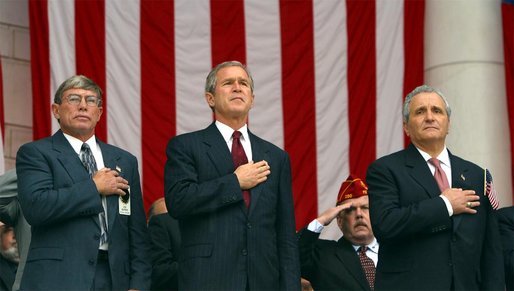 President George W. Bush watches the posting of colors with Joe Burns, National President of Blinded Veterans of America, left, and Anthony Principi, Secretary of Veterans Affairs before giving remarks on Veterans Day at Arlington National Cemetery on Monday November 11, 2002 White House photo by Paul Morse