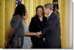 Talking with Dante Nelms, 12, President George W. Bush greets Dante's mother, Pamela Hedrick, right, her husband, Martia Jackson, and her son Darius McIver, 5,(not pictured) during a program honoring graduates of welfare-to-work programs in the East Room Tuesday, Jan. 14, 2003. Ms. Hedrick was on public assistance for eight years in Columbus, Ohio, before volunteering at the Greenbriar Enrichment Center, where she organized a women's support group and received job training.  White House photo by Paul Morse
