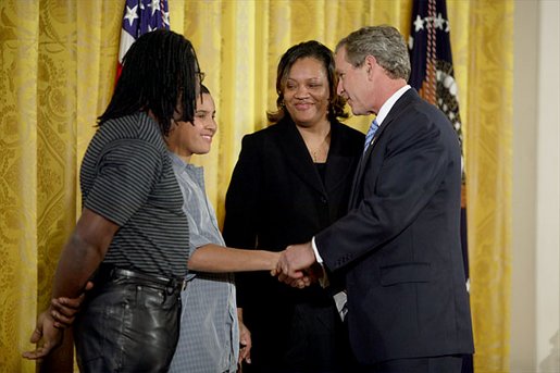 Talking with Dante Nelms, 12, President George W. Bush greets Dante's mother, Pamela Hedrick, right, her husband, Martia Jackson, and her son Darius McIver, 5,(not pictured) during a program honoring graduates of welfare-to-work programs in the East Room Tuesday, Jan. 14, 2003. Ms. Hedrick was on public assistance for eight years in Columbus, Ohio, before volunteering at the Greenbriar Enrichment Center, where she organized a women's support group and received job training. White House photo by Paul Morse.