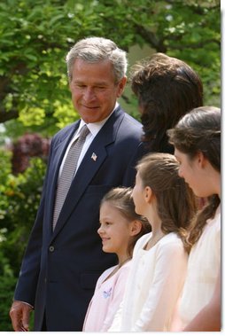 President George W. Bush looks toward Lacy Lyons, center, before signing the S. 151, PROTECT Act of 2003, in the Rose Garden Wednesday, April 30, 2003. Abducted by their father, Lacy, 10, and her sister Nyoka, 8, left, were found after an AMBER alert was activated throughout the state of Florida.   White House photo by Paul Morse