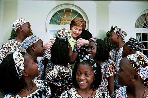 Laura Bush embraces children in the Uganda Children's Choir on the steps of the Oval Office prior to their performance in the Rose Garden June 10, 2003. White House photo by Susan Sterner