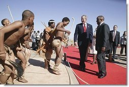 Walking with President Festus Gontebanye Mogae of Botswana, President George W. Bush and Laura Bush (not pictured) are greeted by traditional dancers upon their arrival at Sir Seretse Khama International Airport Thursday, July 10, 2003. 