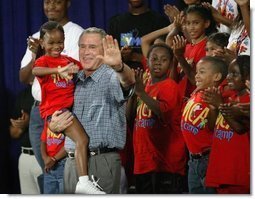 President George W. Bush joins children from Lakewest Family YMCA on stage after speaking on his Health and Fitness Initiative in Dallas, Texas, Friday, July 18, 2003.  White House photo by Eric Draper