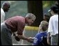 After a game of cheers and close calls, President George W. Bush and Washington Redskin star Darrel Green greet each player with handshakes and an autographed baseball during a ceremony for the White House South Lawn Tee-Ball League Sunday, July 27, 2003. White House photo by Lynden Steele.