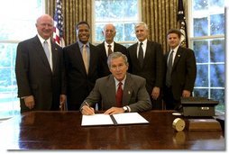 President George W. Bush signs an Executive Order implementing his Volunteers for Prosperity initiative in the Oval Office Thursday, Sept. 25, 2003. Pictured with the President are, from left: Deputy Secretary of Commerce Samuel W. Bodman; Deputy Secretary of Health and Human Services Claude A. Allen; Administrator, Agency for International Development, Andrew Natsios; Under Secretary of State Alan Larson; and Director, USA Freedom Corps, John Bridgeland.  White House photo by Tina Hager