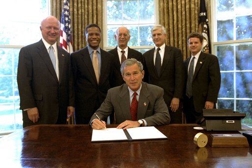 President George W. Bush signs an Executive Order implementing his Volunteers for Prosperity initiative in the Oval Office Thursday, Sept. 25, 2003. Pictured with the President are, from left: Deputy Secretary of Commerce Samuel W. Bodman; Deputy Secretary of Health and Human Services Claude A. Allen; Administrator, Agency for International Development, Andrew Natsios; Under Secretary of State Alan Larson; and Director, USA Freedom Corps, John Bridgeland. White House photo by Tina Hager