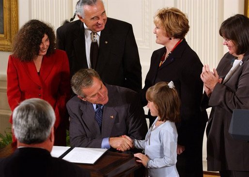 After signing a proclamation recognizing October as Domestic Violence Month, President George W. Bush shakes hands with Monique Blais, 7, the young artist who designed the Stop the Violence postage stamp in the East Room Wednesday, Oct. 8, 2003. White House photo by Tina Hager
