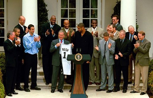 President George W. Bush holds up a jersey presented to him during a ceremony welcoming the 2003 NBA Champion San Antonio Spurs in The Rose Garden Tuesday, Oct. 14, 2003. White House photo by Paul Morse.