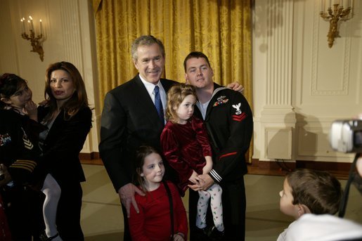President George W. Bush poses for pictures with a soldier and children during a reception held for children of deployed military personnel at the White House Monday, Dec. 8, 2003. A variety of activities were held for the children, including a performance of selected scenes from The Nutcracker and a visit by Santa Claus. White House photo by Eric Draper