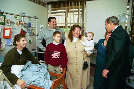 President George W. Bush embraces the mother-in-law of U.S. Army Staff Sergeant Roy Mitchell, who is at left, as other family members look on during the President’s visit to Walter Reed Army Medical Center in Washinton, D.C., Thursday, December 18, 2003. President Bush had just presented Sgt. Mitchell The Purple Heart for injuries sustained while serving in Iraq. Sgt. Mitchell is from Milan, Indiana. Others present are, from left, Jerry Stoneking, Zachary Bice and Sgt. Mitchell's wife, Michelle, who is holding their son Jerrett. White House photo by Eric Draper