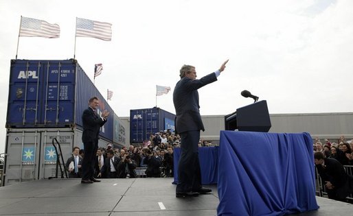 As Homeland Security Secretary Tom Ridge stands nearby, President George W. Bush waves to the audience after delivering remarks on homeland security at the Port of Charleston, S.C., Feb. 5, 2004. White House photo by Paul Morse