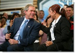 President George W. Bush and accounting clerk Neomi Gonzalez react on stage during a conversation on the economy with employees at Nu-Air Manufacturing Company in Tampa, Florida, Monday, Feb. 16, 2004.  White House photo by Eric Draper