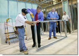 President George W. Bush uses a drill to connect a metal wall frame during a tour of the Carpenters Training Center in Phoenix, Ariz., Friday, March 26, 2004.   White House photo by Eric Draper