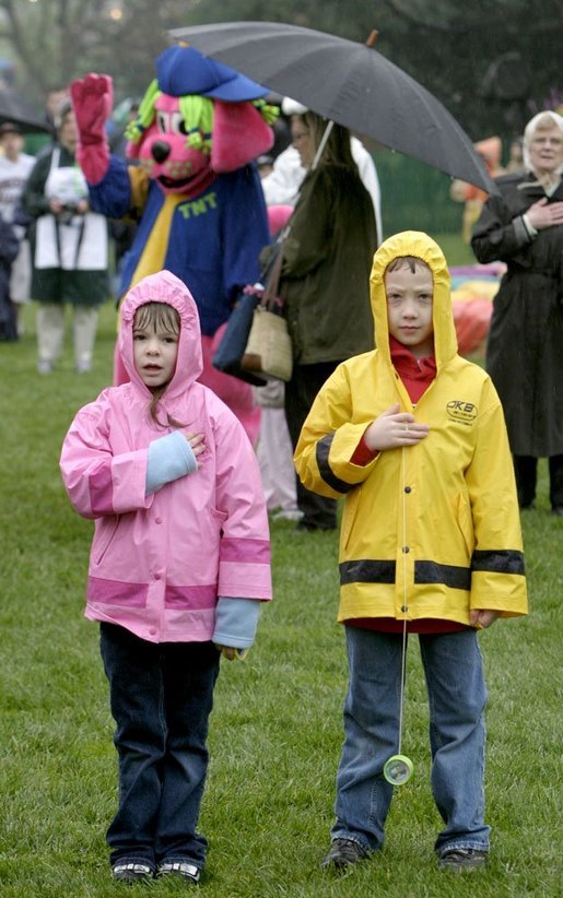 A couple of soaked Easter Egg Roll enthusiasts say the Pledge of Allegiance during the opening ceremonies of the 2004 White House Easter Egg Roll on the South Lawn Monday, April 12, 2004. Despite rain and cold weather, families came out for a morning of Easter eggs and storybook readings. White House photo by Paul Morse.
