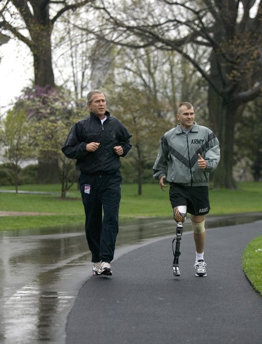 President George W. Bush runs with U.S. Army Staff Sergeant Michael McNaughton, of Denham Springs, La., on the South Lawn of the White House Wednesday, April 14, 2004. The two met January 17, 2003, at Walter Reed Army Medical Center, where SSgt. McNaughton was recovering from wounds sustained in Afghanistan. The President then wished SSgt. McNaughton a speedy recovery so that they might run together in the future. White House photo by Eric Draper.