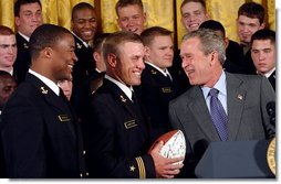 President George W. Bush laughs with Midshipmen Eddie Carthan, left, and team captain Craig Candeto during the presentation of the Commander-In-Chief Trophy to the U.S. Naval Academy football team in the East Room Monday, April 19, 2004. The trophy is awarded to the Service Academy with the year's best overall record in NCAA football games versus the other academies.  White House photo by Tina Hager