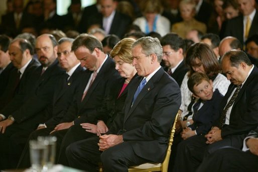President George W. Bush and Laura Bush bow their heads in prayers during a White House ceremony honoring Cinco de Mayo in the East room Wednesday, May 5, 2004. "Mexican Americans have brought many strengths to our nation: a culture built around faith in God, a deep love for family, a belief that hard work leads to a better life," said the President in his remarks. "Every immigrant who lives by these values makes our country better and makes our future brighter." White House photo by Paul Morse