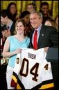 President George W. Bush stands with Kelsey Bills of the University of Minnesota's women's hockey team during a ceremony in the East Room congratulating four NCAA teams for winning national titles Wednesday, May 19, 2004. White House photo by Paul Morse.