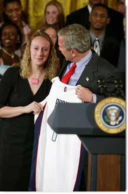 President George W. Bush stands with Maria Conlon of the University of Connecticut women's basketball team during a ceremony in the East Room congratulating four NCAA teams for winning national titles Wednesday, May 19, 2004.  White House photo by Paul Morse