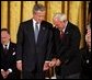 Recipient of the Presidential Medal of Freedom Arnold Palmer compares golf grips with President George W. Bush before receiving his award in the East Room of the White House on June 23, 2004. White House photo by Paul Morse