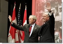 President George W. Bush and Prime Minister Paul Martin wave after their remarks at Pier 21, Canada's historic point of immigration in Halifax, Canada, Dec. 1, 2004. During his remarks, President Bush thanked Canada for the hospitality to more than 33,000 passengers whose airplanes were diverted because of the 911 attacks. "You opened your homes and your churches to strangers. You brought food, you set up clinics, you arranged for calls to their loved ones, and you asked for nothing in return," said the President. White House photo by Paul Morse