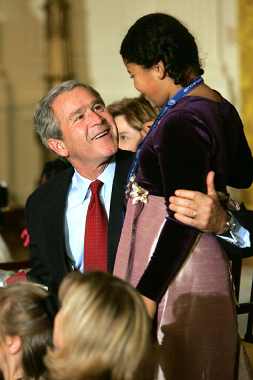 President George W. Bush and Laura Bush join dozens of children to watch a puppet show during the annual Children's Christmas Program in the East Room of the White House, Monday, Dec. 6, 2004. White House photo by Susan Sterner