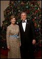 President George W. Bush and Laura Bush stand in front of the official White House Christmas Tree during the 2004 holiday season in the Blue Room of the White House. The White House celebrates the holidays with, "A Season Of Merriment and Melody," and include items like 350 instrument ornaments that adorn the Blue Room tree. White House photo by Eric Draper