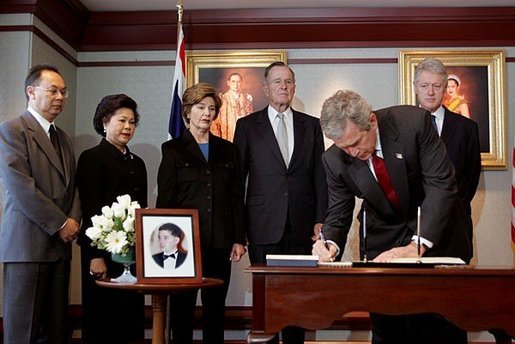 President George W. Bush signs a condolence book for the victims of the recent tsunami during a visit to the Embassy of Thailand in Washington, D.C., Monday, Jan. 3, 2005. Next to the book, stands a photograph of Khun Poom Jensen, 21. A grandson of Thailand's King Bhumibol Adulyadej, Mr. Jensen died in the tsunami. Also signing their condolences are Laura Bush and former Presidents Bush and Clinton. White House photo by Susan Sterner.