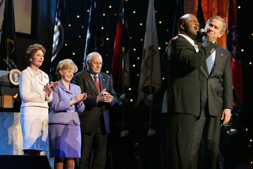 President George W. Bush puts his arm around Singer Bebe Winans as he sings 'God Bless America' during the 'Saluting Those Who Serve' event at the MCI Center in Washington, D.C., Tuesday, Jan. 18, 2005. Also pictured are, from left, Laura Bush, Lynne Cheney, and Vice President Dick Cheney. White House photo by David Bohrer