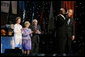President George W. Bush puts his arm around Singer Bebe Winans as he sings 'God Bless America' during the 'Saluting Those Who Serve' event at the MCI Center in Washington, D.C., Tuesday, Jan. 18, 2005. Also pictured are, from left, Laura Bush, Lynne Cheney, and Vice President Dick Cheney. White House photo by David Bohrer